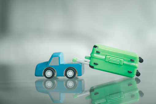 Miniature wood blue toy car with green suitcase. Concept of travel in new normal