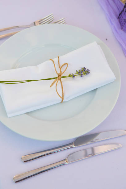 istock Elegant table setting for wedding engagement Easter dinner with white ceramic plates cotton napkin tied with twine lavender flowers candles. Provence style 1254087225
