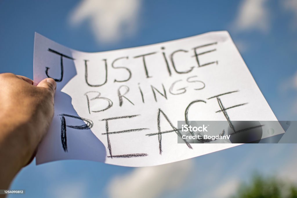 Messages sent during the protest in Hollywood. "Justice brings peace". Banner held in the hands of the protester. Blue sky in the background. City Of Los Angeles Stock Photo