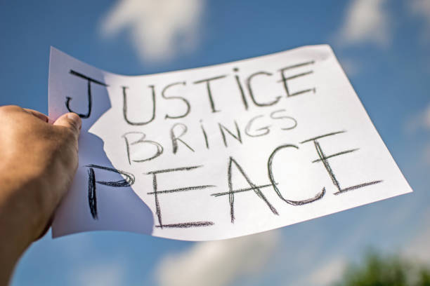 Messages sent during the protest in Hollywood. "Justice brings peace". Banner held in the hands of the protester. Blue sky in the background. george floyd protests stock pictures, royalty-free photos & images