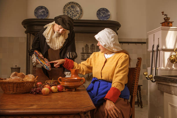 Portrait of a beautiful historical dutch milk maid and a nobleman Portrait of a beautiful historical dutch milk maid and a nobleman wearing historically correct outfits in a typical townhouse kitchen dutch baroque architecture stock pictures, royalty-free photos & images