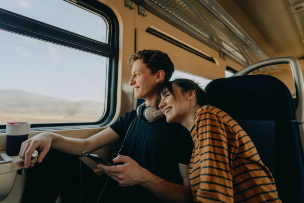 Travelling together Photo of a smiling young couple travelling together by train fall travel stock pictures, royalty-free photos & images