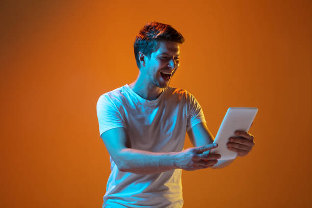 istock Caucasian beautiful young man's portrait on gradient orange studio background, emotional and expressive. Copyspace for ad. 1254092626