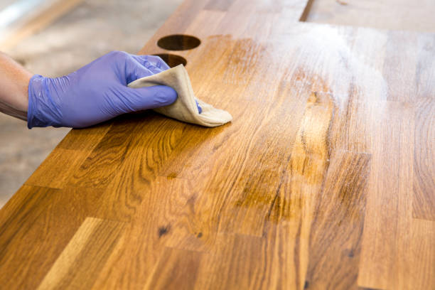 persona que trabaja, frotando el engrase con linaza aceite de encimera de madera natural antes de usar. concepto de mantenimiento de encimera de bloque de carnicero de madera maciza. - barnizado de madera fotografías e imágenes de stock