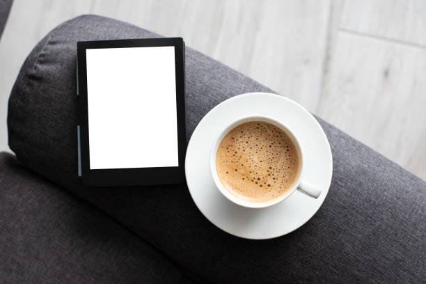 Mockup Ebook on soft modern armchair With Blank White Screen, to replace your design. Cup of Coffee for cozy atmosphere reading. Paste your book cover here