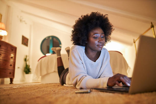istock Serene young woman lying on the floor in bedroom while using a laptop computer 1254097206