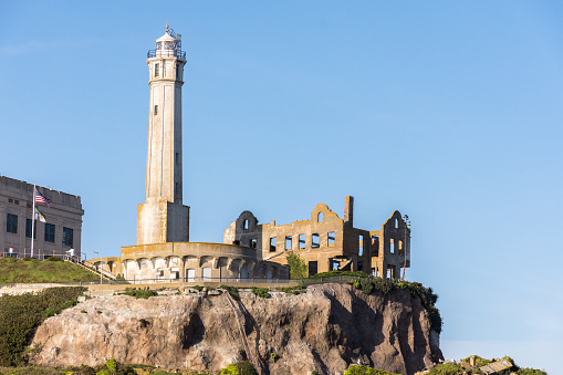 Lighthouse on Alcatraz Island viewed from San Francisco Bay in full sun with ruins.