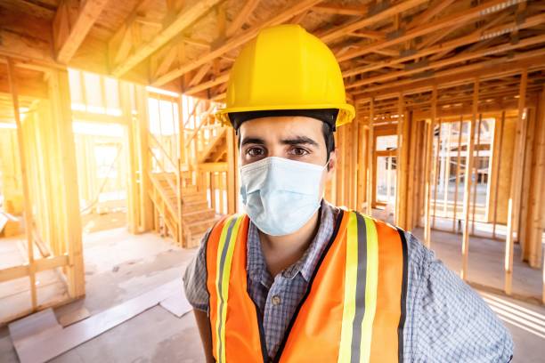 istock Young male construction worker looking at the camera wearing a protective face mask 1254109965