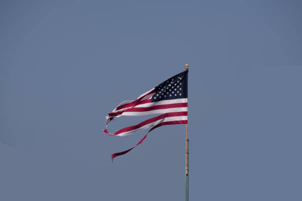 A shredded American flag against a clear blue sky seems symbolic of the divide in America.