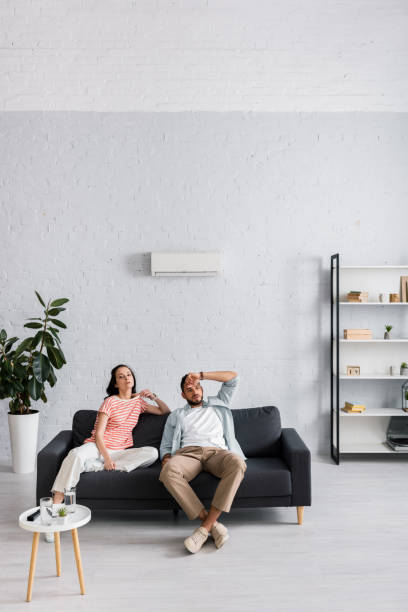 istock Young couple feeling hot while sitting on sofa at home 1254115352