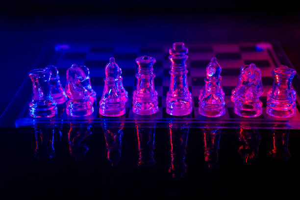 istock Photograph the chess pieces on the board reflecting in a mirror illuminated with colored lights. 1254116316