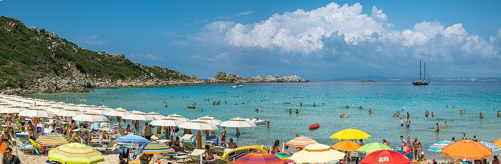 Santa Teresa Gallura, Italy - August 29, 2019: Crowd of people enjoying sun on beach in Santa Teresa Gallura, in Sardinia, Italy during hot summer day in August 2019