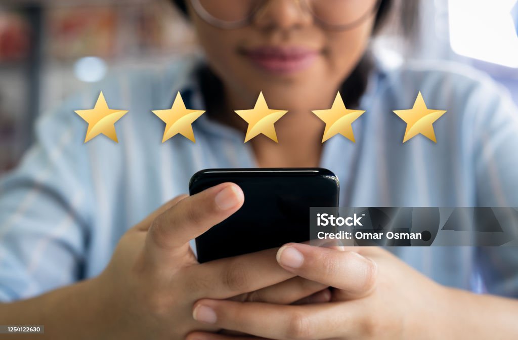 Woman using cell phone with 5 gold star customer satisfaction graphic 5 star customer experience satisfaction score with gold stars and satisfied customer filling in business survey Feedback Stock Photo