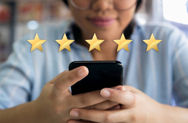 Woman using cell phone with 5 gold star customer satisfaction graphic 5 star customer experience satisfaction score with gold stars and satisfied customer filling in business survey first class stock pictures, royalty-free photos & images