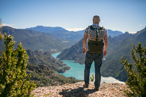 Traveler stands alone on top of the mountain and looking forward on a river in the valley