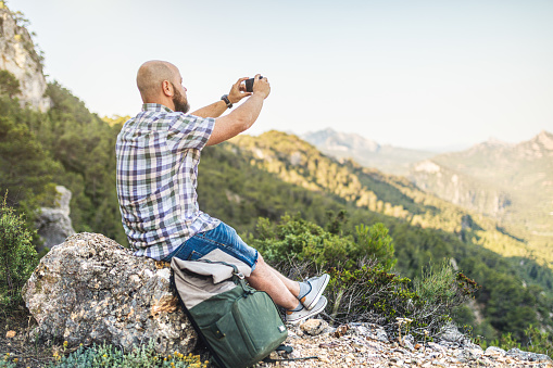 Man with backpack uses smartphone in the mountains