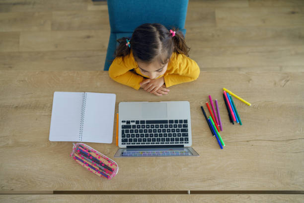 istock Little girl doing her homework with laptop 1254125163