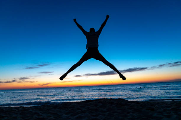 Silhouette of jumping man on sunrise background