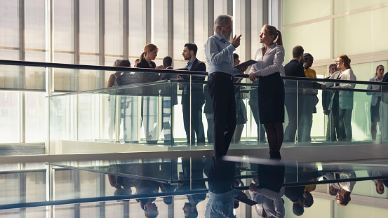 Two business people standing in front of a large group in the office building