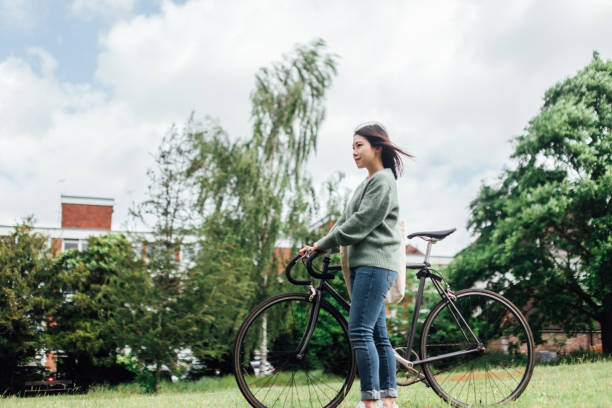 młoda kobieta z rowerem relaks w parku - mental health women asian ethnicity bicycle zdjęcia i obrazy z banku zdjęć
