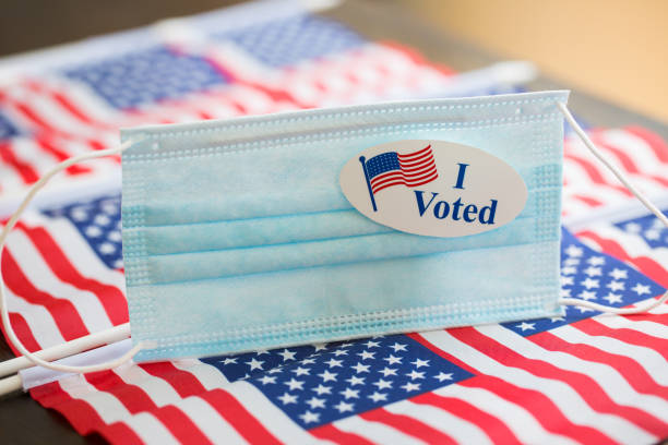 istock Vote sticker on face masks and american flags 1254131242