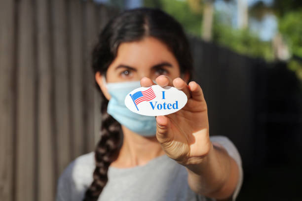 Young woman wearing face mask holding I voted today sticker Young woman wearing face mask holding I voted today sticker. midterm election photos stock pictures, royalty-free photos & images