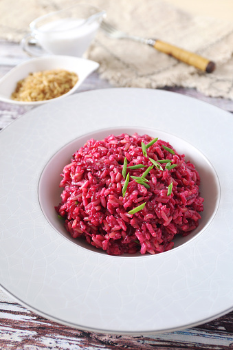 Pink rice. Beetroot risotto from brown rice with almond milk, chives onion dressing. Diet food.