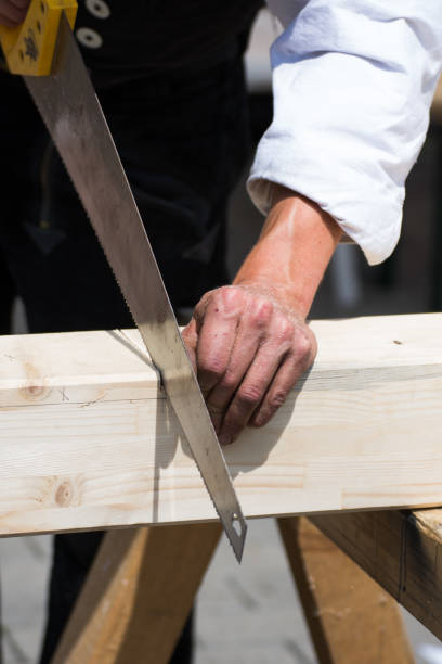 istock Carpenter sawing a board with a hand wood saw 1254142251