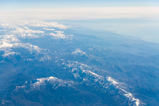 Mountain range in Caucasus mountains with snowy tops. Black sea coast on the left. Aerial view from the plane