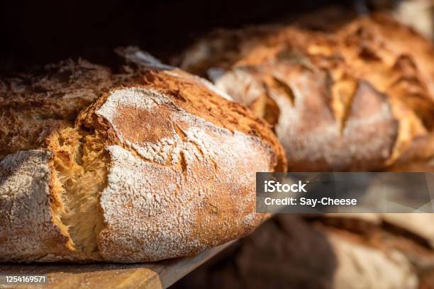 Sourdough Bread On Wooden Shelves Bakery Shelf With Golden Crust Bread Stock Photo - Download Image Now