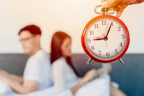 alarm clock with blur people sitting facing back for bad relationship times of living together family hours or couple lover boring each other concept. - waiting women clock boredom imagens e fotografias de stock