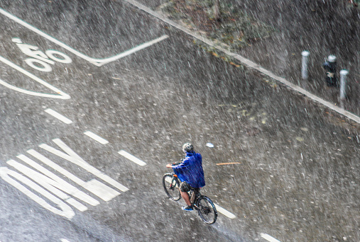 Delivery man riding bike in a severe hailstorm on the street in Manhattan