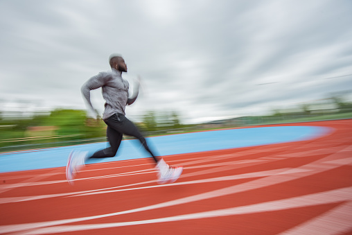 Young African American man running at tartan.