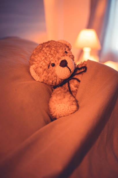 istock Cute wool teddy bear is lying in the bed 1254181459