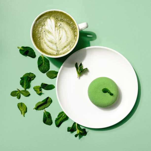Top view. Hot tea matcha latte milk cup and coffee cup in coffee shop cafe on green background. Creative layout made of apple and mint. Green healthy juice with fruits and herbs
