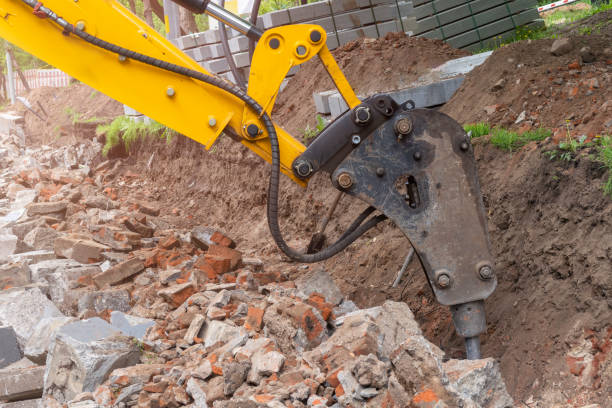 istock Excavator arm with hydraulic hammer breaker destroying brick wall 1254194618