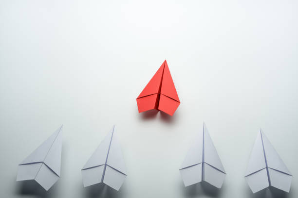 istock Leadership concept with red paper plane leading among white on white background 1254196100
