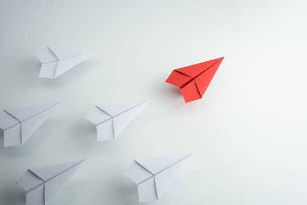 istock Leadership concept with red paper plane leading among white on white background 1254196396