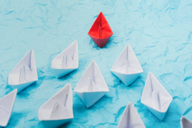 istock Leadership concept with red paper ship leading among white 1254197190