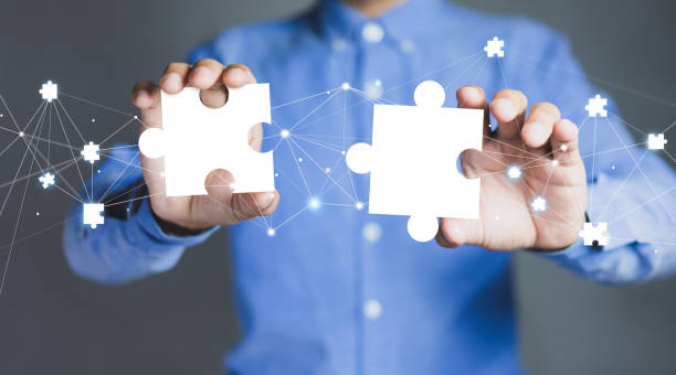 Businessman hands connecting puzzle pieces representing the merging of two companies or joint venture, partnership, Mergers and acquisition concept. stock photo