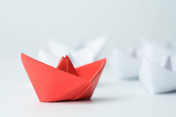 istock Leadership concept with red paper ship leading among white on white background. 1254197344