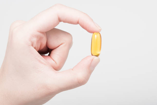 istock Yellow Omega 3 capsule squeezed in fingers 1254197387
