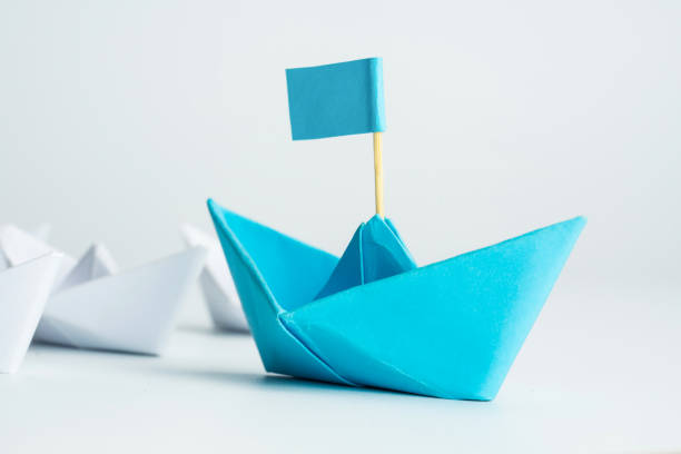 istock Leadership concept with blue paper ship leading among white 1254197409