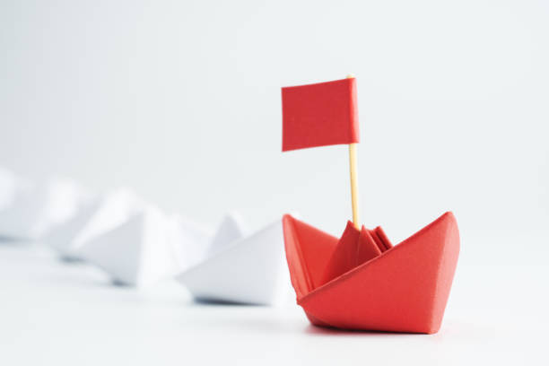 istock Leadership concept with red paper ship leading among white 1254197446