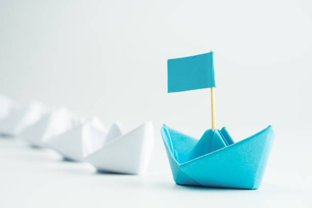 istock Leadership concept with blue paper ship leading among white 1254197488
