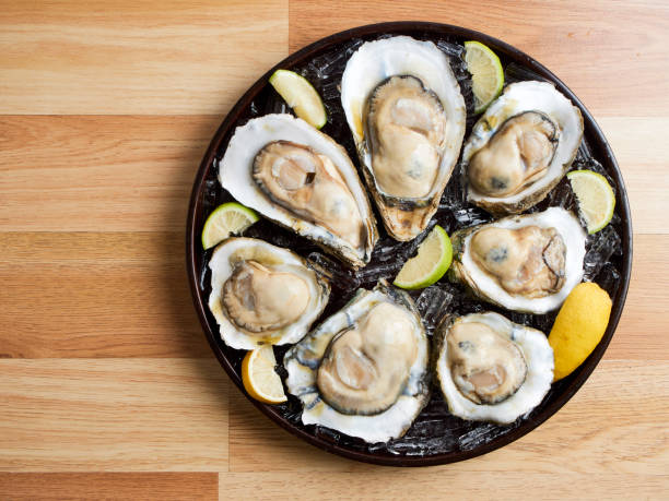 istock Oysters on ice and lemon in a tray on wooden table 1254198313