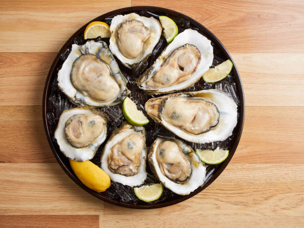 氷の上のカキと木製のテーブルのトレイにレモン - prepared oysters prepared shellfish shucked seafood ストックフォトと画像