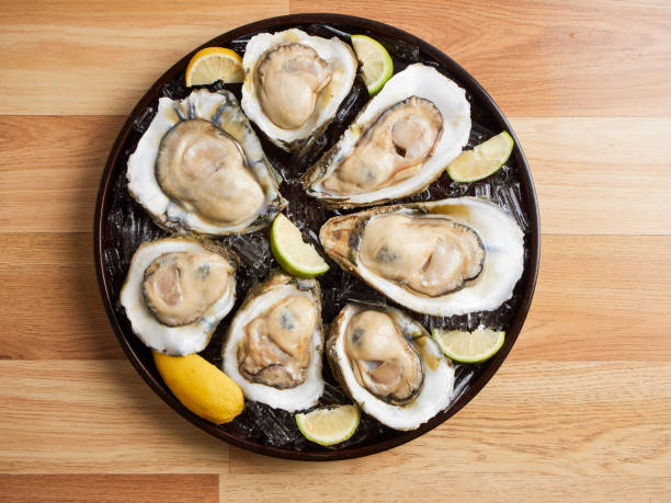 istock Oysters on ice and lemon in a tray on wooden table 1254198315