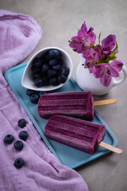 Homemade blueberries popsicles on gray background