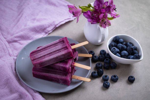 Homemade blueberries popsicles on gray background